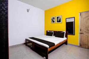 a bed in a room with a yellow wall at Hotel O Kunal guest house in Goa +37 photos