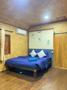a bedroom with a bed with blue sheets and pillows at Panan Homestay Kohpu in Ban Na