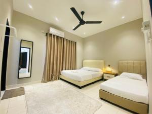 a bedroom with two beds and a ceiling fan at Hanah Home Pagoh in Pagoh