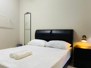 a bed with a black headboard and two towels on it at Hanah Home Pagoh in Pagoh