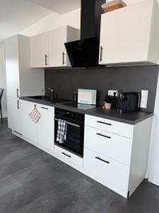 a kitchen with white cabinets and a stove top oven at Ferienwohnung Verissimo in Ittlingen