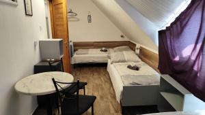 a room with two beds and a table and a table at Arcadia Guesthouse in Ábrahámhegy