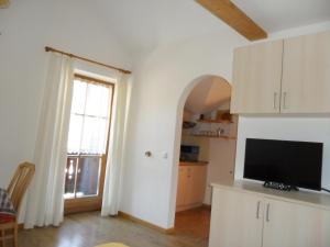 a living room with a television and a large window at Appartamenti Stauderhof in Villabassa
