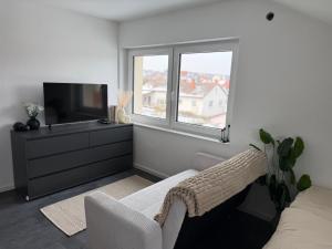 a living room with a television and a white couch at Ferienwohnung Verissimo in Ittlingen
