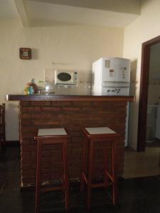 cocina con encimera con microondas y 2 taburetes en Casa aconchego Geribá canto direito 2Q com WiFi, en Búzios