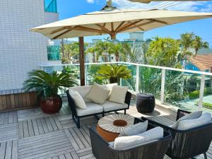 a patio with chairs and an umbrella and a table at Excelente Apto no condomínio Boulevard in Bombinhas