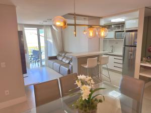 a kitchen and living room with a glass table with flowers at Excelente Apto no condomínio Boulevard in Bombinhas