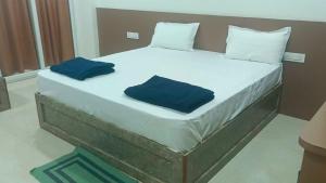 a large bed with two blue pillows on it at Hotel O V GUEST INN in Bhattiprolu