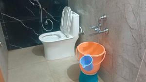 a bathroom with a toilet and a bucket at Hotel O V GUEST INN in Bhattiprolu