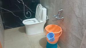 a bathroom with a toilet and a bucket at Hotel O V GUEST INN in Bhattiprolu