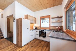 eine Küche mit weißen Geräten und einer Holzdecke in der Unterkunft Chalet Modriach - Private Sauna & Whirlpool in Modriach