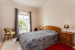a bedroom with a bed and a chair and a window at Villa Coelho by Trip2Portugal in Olhão