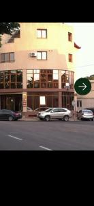 a building with cars parked in front of a street at Rotonda apartment in Lugoj