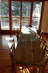 a wooden table with chairs in a room with windows at Apartment mit Balkon by Interhome in Padola