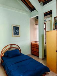 a bedroom with a blue bed and a wooden dresser at Widi House in Nusa Dua