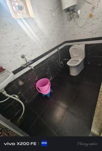a bathroom with a pink bucket next to a toilet at Hotel karishna palace in Rīngas