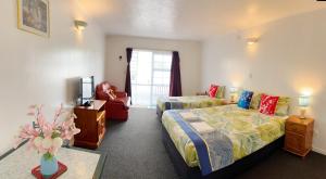 a bedroom with a bed and a couch and a chair at Kerry's Motel in Rotorua