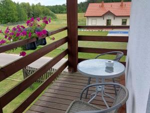 a table and chairs on a wooden deck with flowers at Apartment by Interhome in Łukta