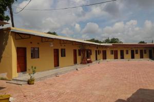 a yellow building with a brick courtyard in front of it at Infinity 555 Lodge in Lusaka