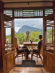 a man and woman sitting at a table with a view of a mountain at Eden View Ella - Tour options in the area in Ella