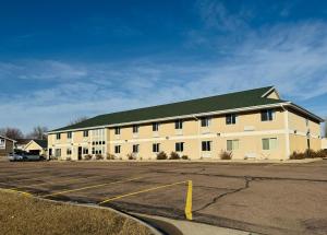 a large white building with a green roof at Bilmar Inn & Suites Dell Rapids Near Sioux Falls in Dell Rapids