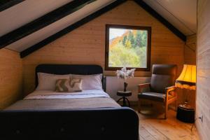a bedroom with a bed and a chair in a attic at Cabana Murmur -Riverside- in Valea Ierii