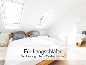 a white bedroom with a bed and a window at Casa Ueberall - Ruhige DG-Ferienwohnung für 2 Erwachsene in Burg - Balkon mit Abendsonne, hochwertige Ausstattung, überdachter E-Bike-Stellplatz, Nähe zur Altstadt & Restaurants in Fehmarn