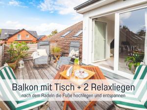 a balcony with a wooden table and chairs on a house at Casa Ueberall - Ruhige DG-Ferienwohnung für 2 Erwachsene in Burg - Balkon mit Abendsonne, hochwertige Ausstattung, überdachter E-Bike-Stellplatz, Nähe zur Altstadt & Restaurants in Fehmarn