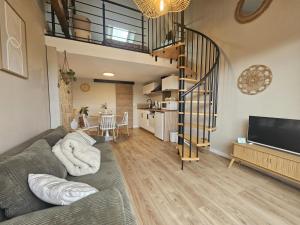a living room with a couch and a spiral staircase at L'arbre de soie - l'acacia in Vouillé