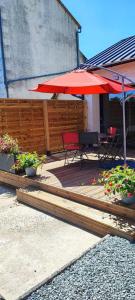 a patio with a table and a red umbrella at L'arbre de soie - l'acacia in Vouillé