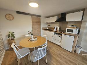 a kitchen with a table and chairs in a room at L'arbre de soie - l'acacia in Vouillé