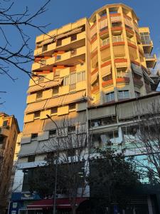 a tall yellow building with windows at Centralin Apartotel in Tirana