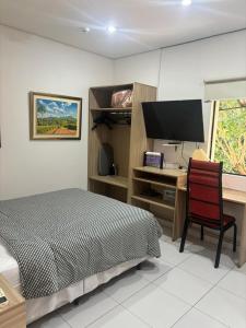 a bedroom with a bed and a desk with a monitor at Aparthotel Maison Suisse in Asunción