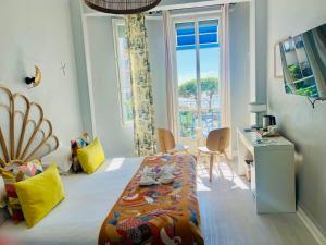 a bedroom with a bed and a desk and a window at Hôtel Eden - La Baigneuse in Juan-les-Pins