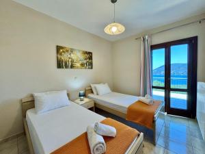 two beds in a room with a view of the ocean at Villa Vassilis Fiscardo Kefalonia in Katsaráta +37 photos