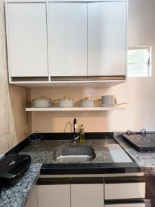 a kitchen counter with a sink and white cabinets at Apartamento juçara Lençóis in Barreirinhas