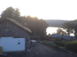 a stone building with a white garage next to a lake at Artie's Lodge in Windermere