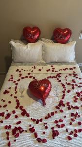 a bed with red petals on it with hearts on it at Pousada Green House Paraty in Paraty