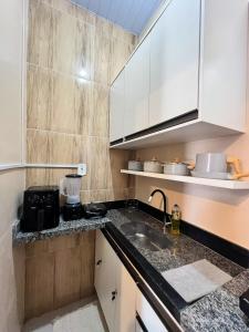 a small kitchen with white cabinets and a sink at Apartamento juçara Lençóis in Barreirinhas +7 photos