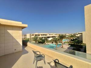 a balcony with two chairs and a view of a pool at View Pool Apartment, Two Rooms in El Gouna