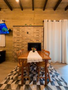 a dining room table with chairs and a fireplace at Pousada Duas Marias in Nova Veneza