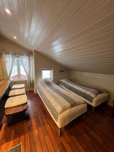 two beds in a room with wooden floors at Visit Leif at Senja in Gibostad