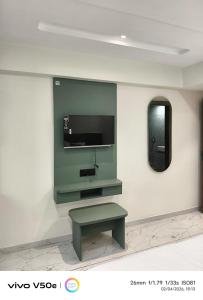 a living room with a bench and a tv on a wall at Hotel 7 CR in Ahmedabad
