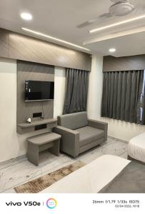 a living room with a couch and a tv at Hotel 7 CR in Ahmedabad