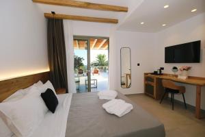 a bedroom with a bed with a desk and a television at Platy Beach Hotel in Platy