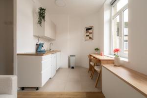 a kitchen with white cabinets and a wooden table at Le Cocoon Studio 2 voyageurs in Arras