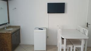 a kitchen with a table and a white refrigerator at Vista Beach Ingleses in Florianópolis