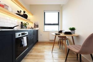 a kitchen with black cabinets and a small table at The Swansea Central Hall 1 Bed Room Apartment in Swansea