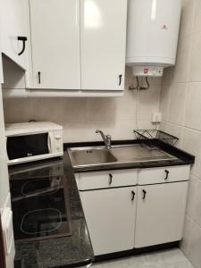 a kitchen with white cabinets and a sink and a microwave at María II in Ferrol +2 photos