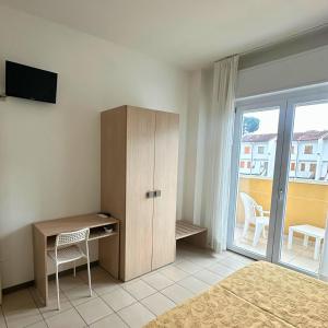 a bedroom with a desk and a cabinet and a window at Hotel Furga B&B in Cervia